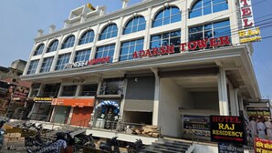 A hotel named "Adarsh Tower" with a sign indicating "Hotel Raj Residency" and "Vivo Authorized Service Center".