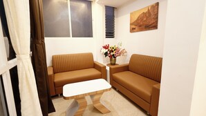 A modern living room with two brown sofas, a white coffee table, and a vase of flowers.