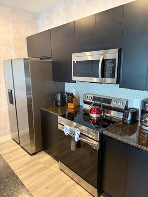 A modern kitchen with stainless steel appliances, a microwave, a kettle, and a toaster. - Magic Spring (Kissimmee)