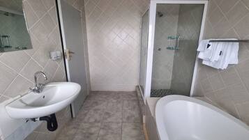 Une salle de bain équipée d’un lavabo, de toilettes, d’une douche et d’une baignoire.