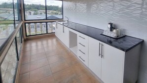 Una cocina con encimera negra, armarios blancos y vistas amplias por un ventanal.
