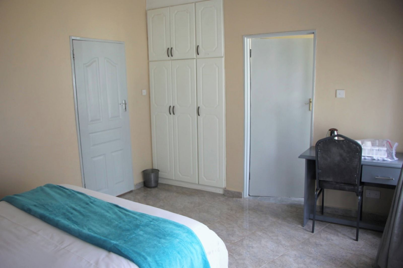 A bedroom with a bed, a desk, and a wardrobe.