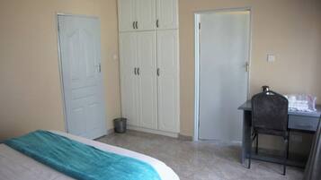 A bedroom with a bed, a desk, and a wardrobe.
