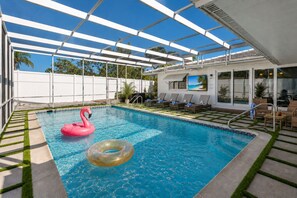 A swimming pool with a glass ceiling, lounge chairs, and a view of the outdoors. - Private Pool Oasis Near Anna Maria Island + Tiki Bar + Games + Sleeps 12 (Bradenton)