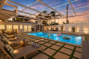 A pool area with lounge chairs, a flamingo float, and a covered seating area. - Private Pool Oasis Near Anna Maria Island + Tiki Bar + Games + Sleeps 12 (Bradenton)
