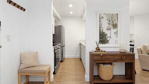 A modern kitchen with stainless steel appliances, a wooden bench, and a console table with a woven basket. - Fallridge Condo - Steps to Nordic Center & Bus (Vail)