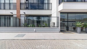 A modern building with a glass entrance, potted plants, and a paved walkway. - Studio in Condo w/ Pool and Gym Cuo0114 (Florianópolis)