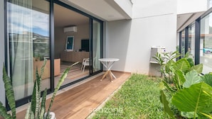 A modern apartment with a glass door leading to a living area, a small round table, and a potted plant. - Studio in Condo w/ Pool and Gym Cuo0114 (Florianópolis)