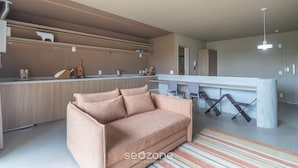 A modern kitchen with a sofa, a dining area, and a bar. - Studio in Condo w/ Pool and Gym Cuo0114 (Florianópolis)