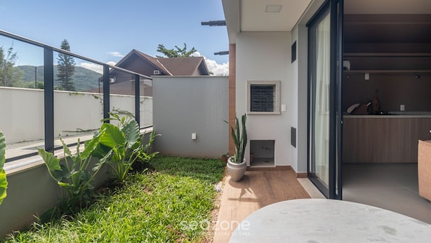 A modern house with a patio, a sliding glass door leading to a kitchen, and a view of the surrounding landscape. - Studio in Condo w/ Pool and Gym Cuo0114 (Florianópolis)