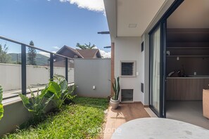 Ein modernes Haus mit Terrasse, einer Schiebetür zu einer Küche und Blick auf die umliegende Landschaft.