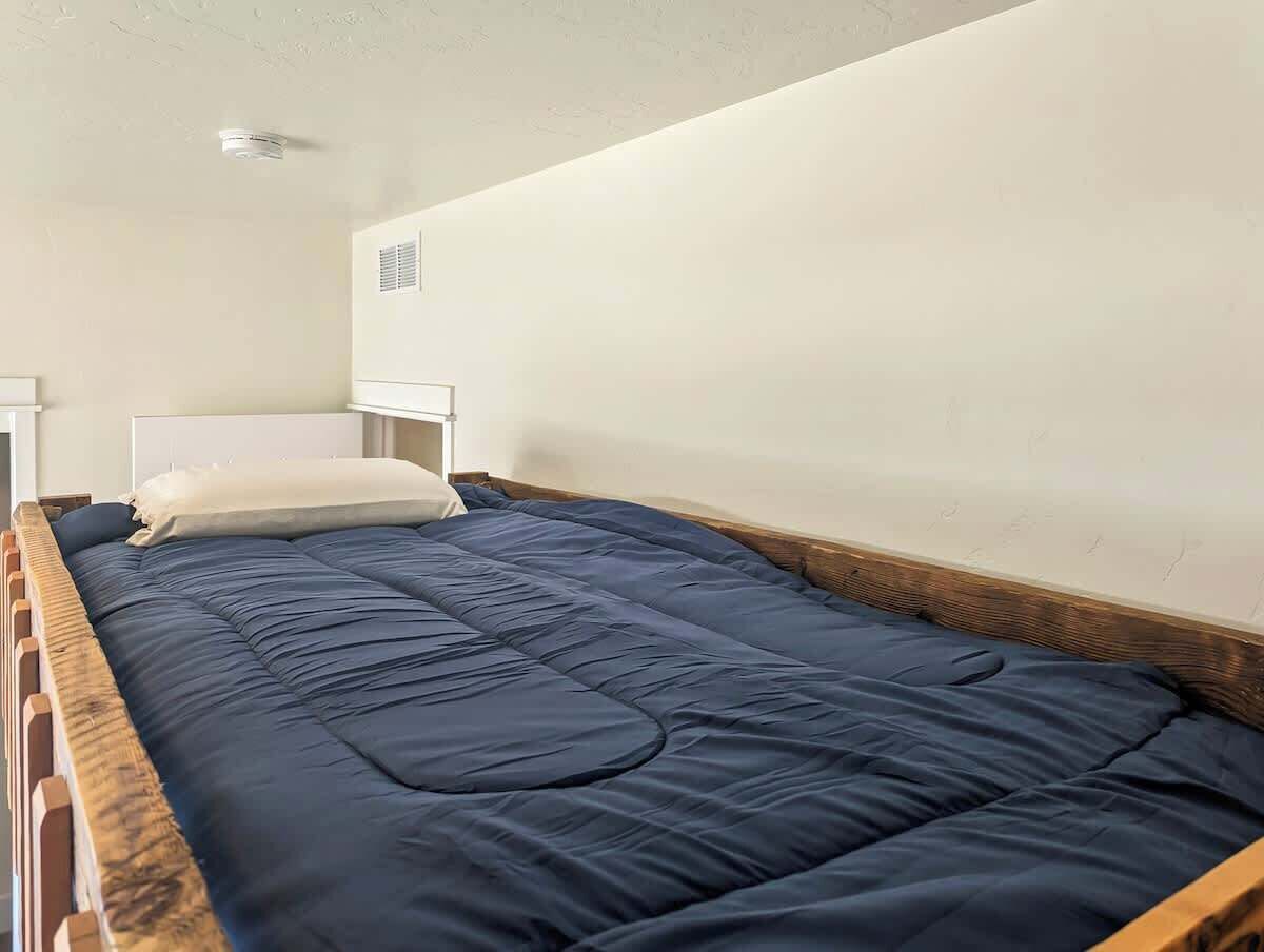 Een eenpersoonsbed met houten frame en een donkerblauwe matras.