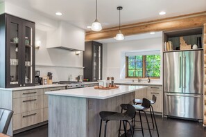 Una cocina moderna con una isla central, electrodomésticos de acero inoxidable y vigas de madera en el techo.