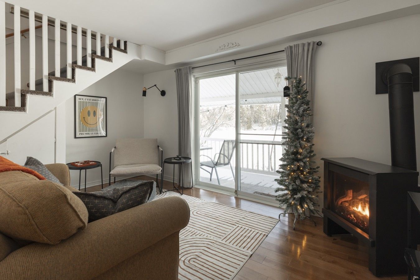 A living room with a sofa, a chair, a small table, a fireplace, and a staircase.
