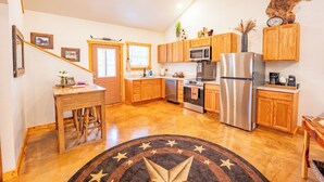 A kitchen with wooden cabinets, stainless steel appliances, and a star-patterned rug.