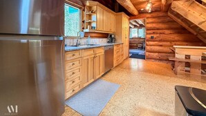 Una cocina con armarios de madera, un refrigerador de acero inoxidable y una lámpara colgante.