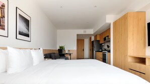 Een moderne hotelkamer met een groot bed, een klein bureau, een stoel, een televisie en een kitchenette.
