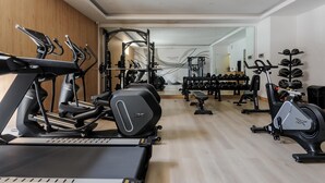Een moderne sportschool met diverse cardioapparaten, krachthonderdelen en een spiegelwand.