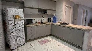 Una cucina moderna con mobili grigi, un forno a microonde, una macchina da caffè e un dispenser per l'acqua.