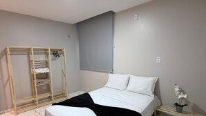 Una camera da letto con un letto, un armadio in legno, un comodino e un tavolino con una pianta in vaso.
