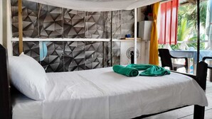Un lit avec un drap blanc, une serviette verte et un oreiller blanc.