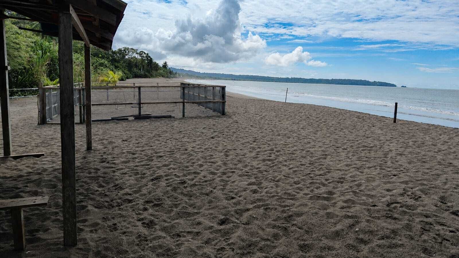 Une plage avec une structure en bois, un banc et une vue sur l’océan.
