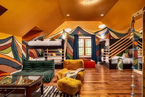 Un dormitorio ático acogedor con literas, un sofá, una mesa de centro y un mural colorido en las paredes.