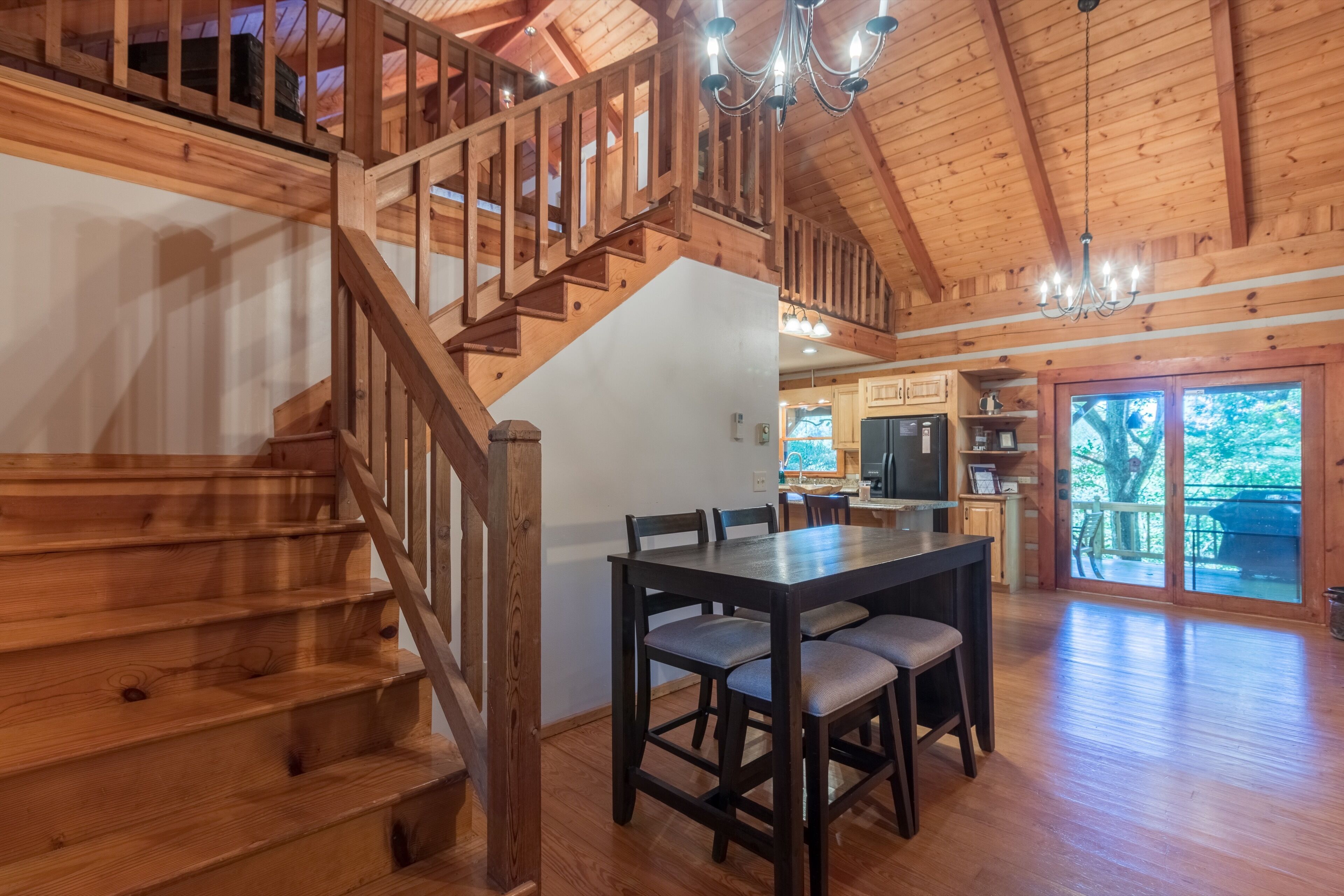 A wooden staircase leading to a loft bedroom with a chandelier.