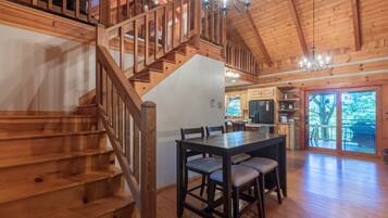 A wooden staircase leading to a loft bedroom with a chandelier.