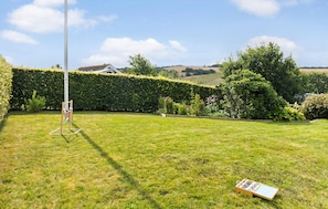 A grassy outdoor area with a metal structure, a hedge, and a wooden box. - 2 bedroom cozy home in Roslev (Roslev)