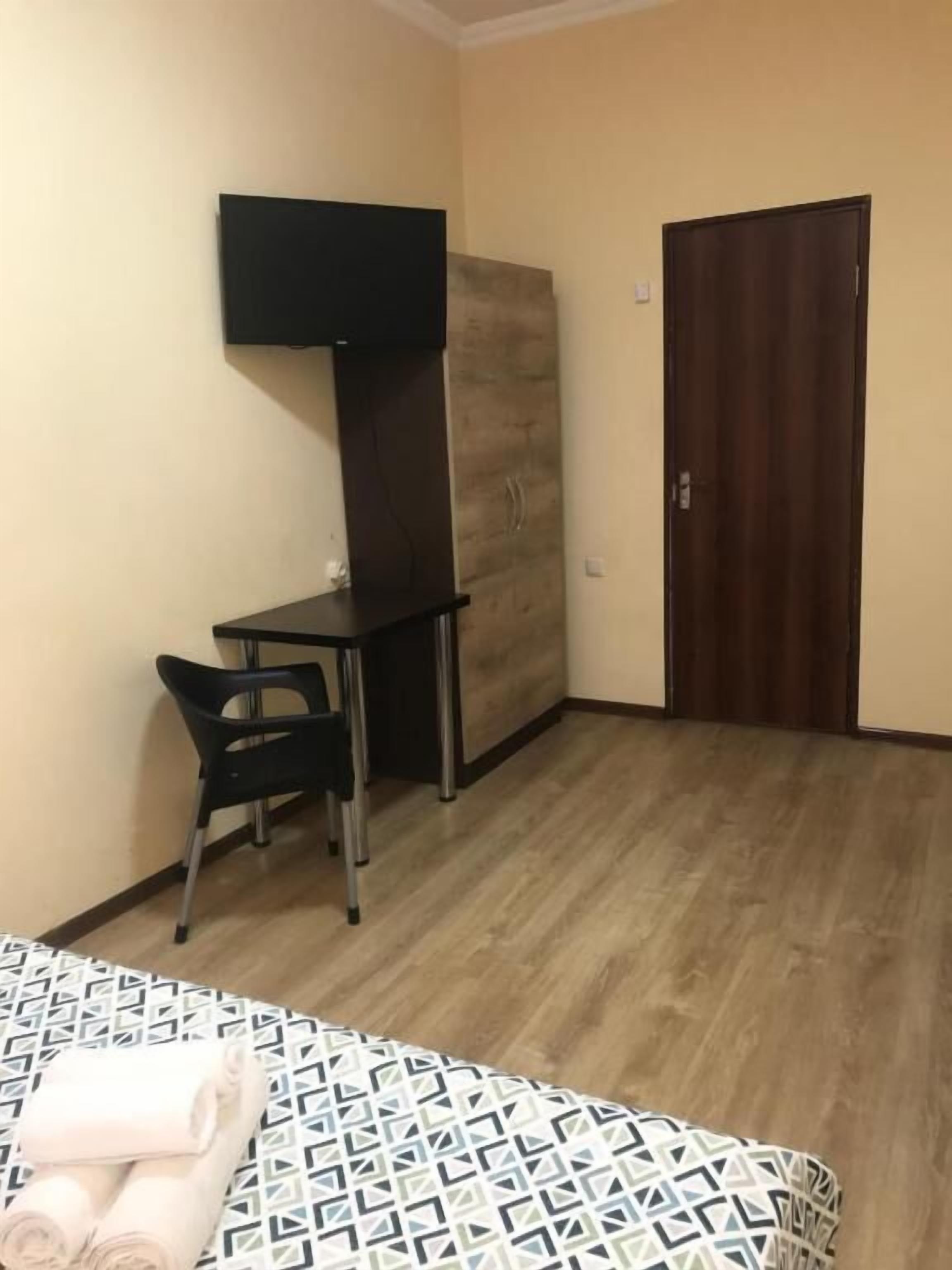 A room with a bed, a desk, a chair, a wardrobe, and a door.