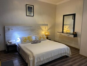 Ein ordentlich eingerichtetes Schlafzimmer mit einem großen Bett, einem Nachttisch, einer Wandablage und einem Spiegel.