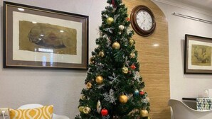 A Christmas tree decorated with gold ornaments and a clock on the wall. - Guest House Aygestan Hotel (Yerevan)