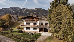 Un chalet à deux étages doté d’un balcon, entouré d’un jardin bien entretenu et avec une vue sur les montagnes.