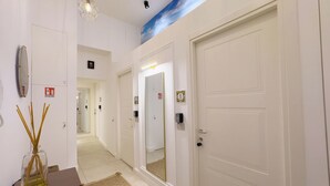 A hallway with white doors, a mirror, a vase with reed sticks, and a ceiling with a cloud design. - A CASA TUA  (Naples)