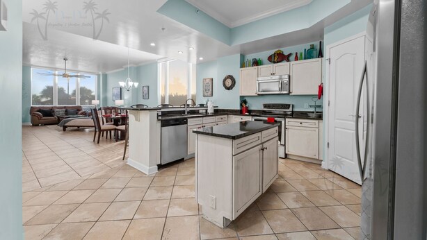 A spacious kitchen with white cabinets, a central island, and a refrigerator. - Sienna on the Coast 107 | Beautiful Unit on the Ground Floor! (Gulfport)