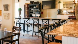 Una zona de bar con mostrador, taburetes y un televisor en la pared.