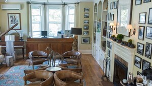 Un amplio salón con un piano, sillones de cuero, una chimenea y una pared decorada con cuadros.