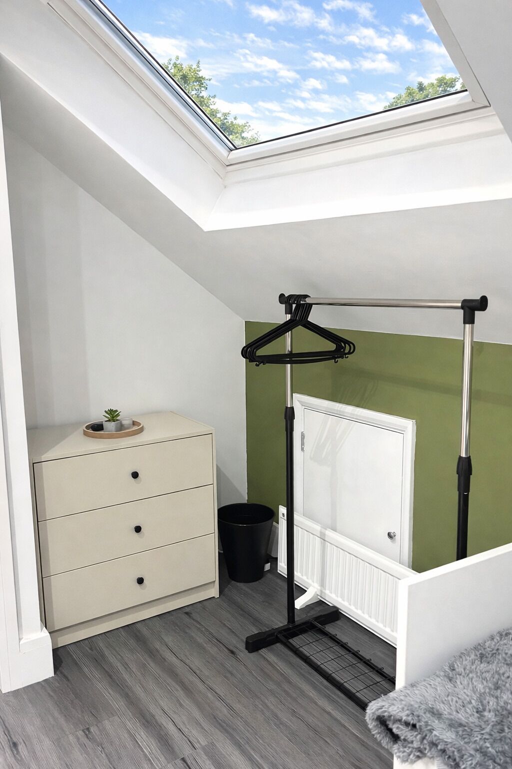 Une pièce de taille modeste, dotée d’un puits de lumière, d’un radiateur, d’une petite commode et d’un cache-radiateur.