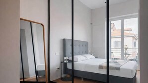 Une chambre à coucher moderne avec un grand lit, une table de chevet et un miroir.