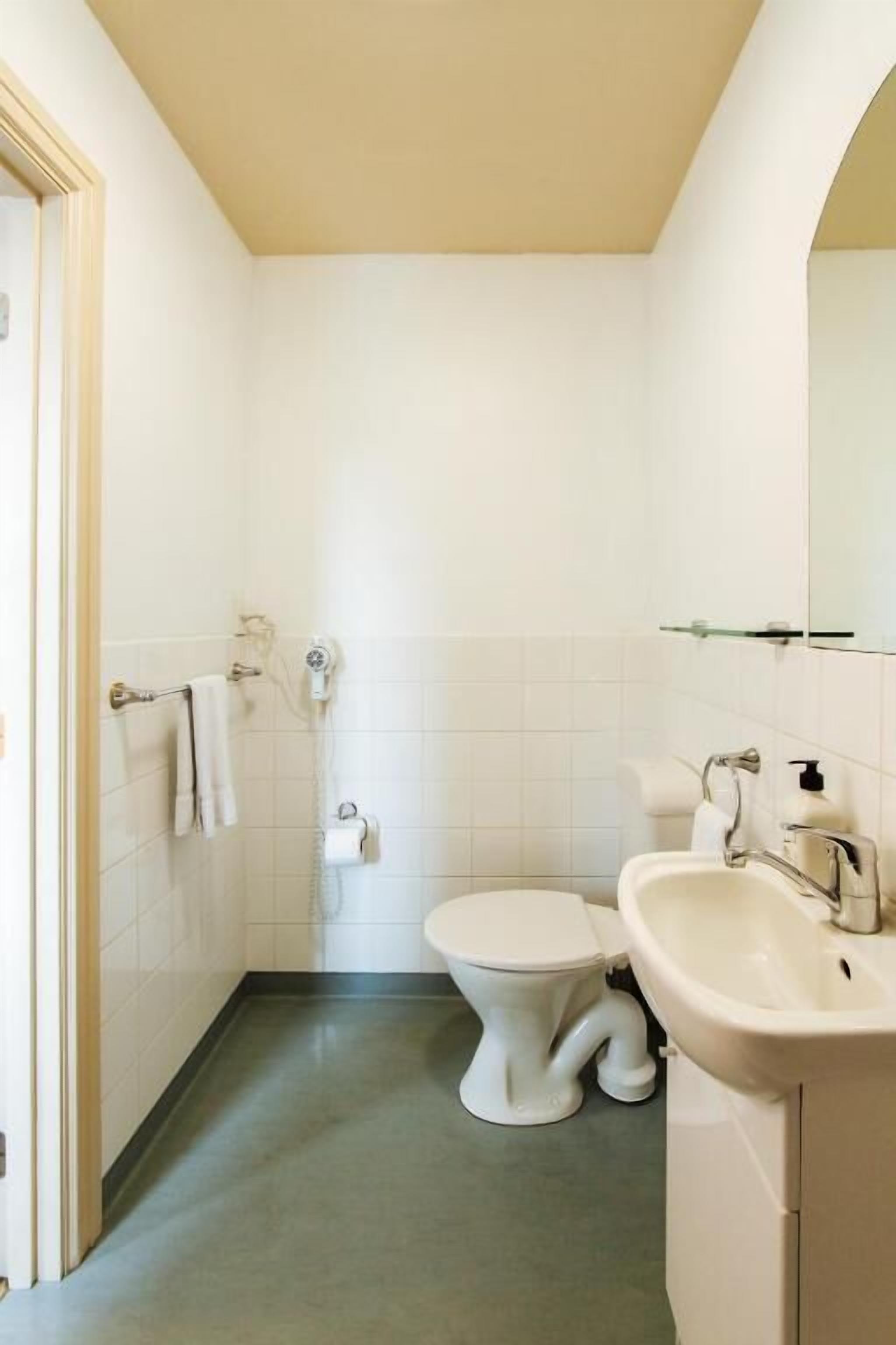 A small, clean bathroom with a toilet, sink, and towel rack.