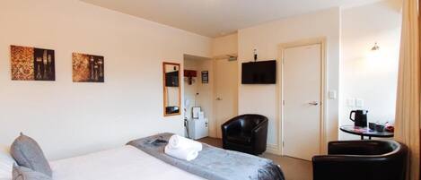 Habitación de hotel con cama, escritorio, silla, televisor y obras de arte en la pared.