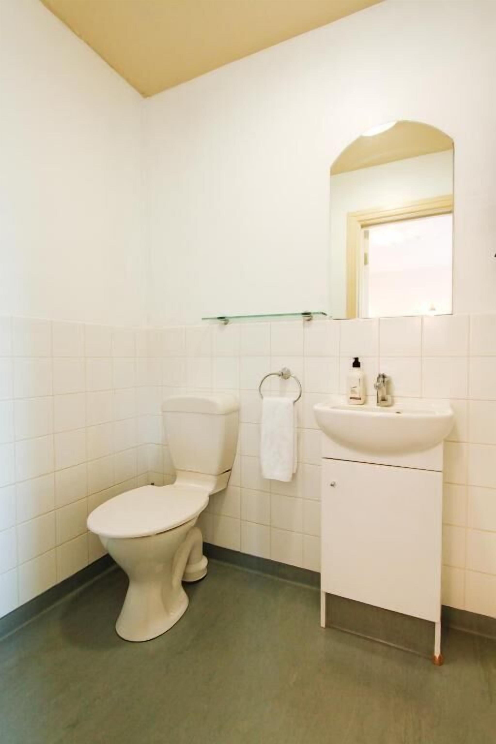 Ein kleines, sauberes Badezimmer mit Toilette, Waschbecken und Spiegel.