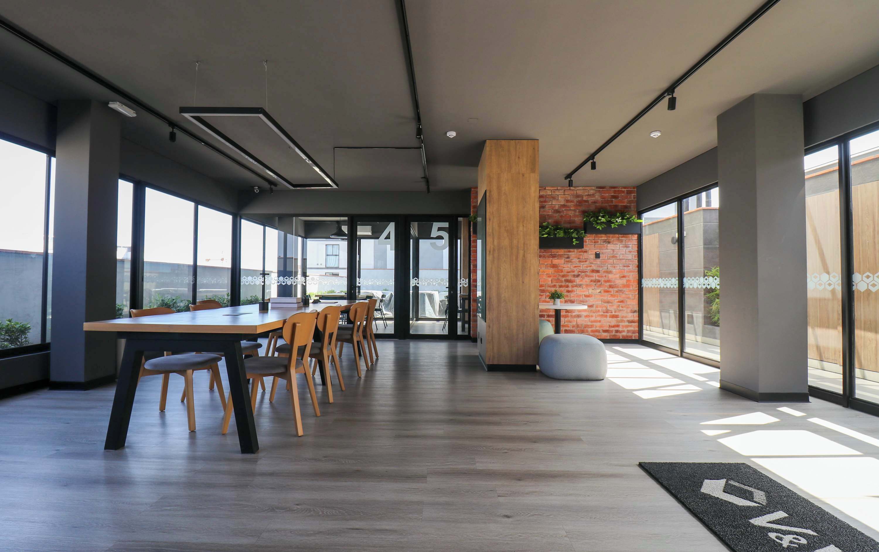 A modern office space with a large table, chairs, and a brick accent wall.