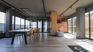 Een moderne kantoorruimte met een grote tafel, stoelen en een accentmuur van baksteen.