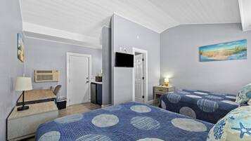 Quarto com duas camas, uma escrivaninha, uma cadeira, uma televisão e um quadro na parede.