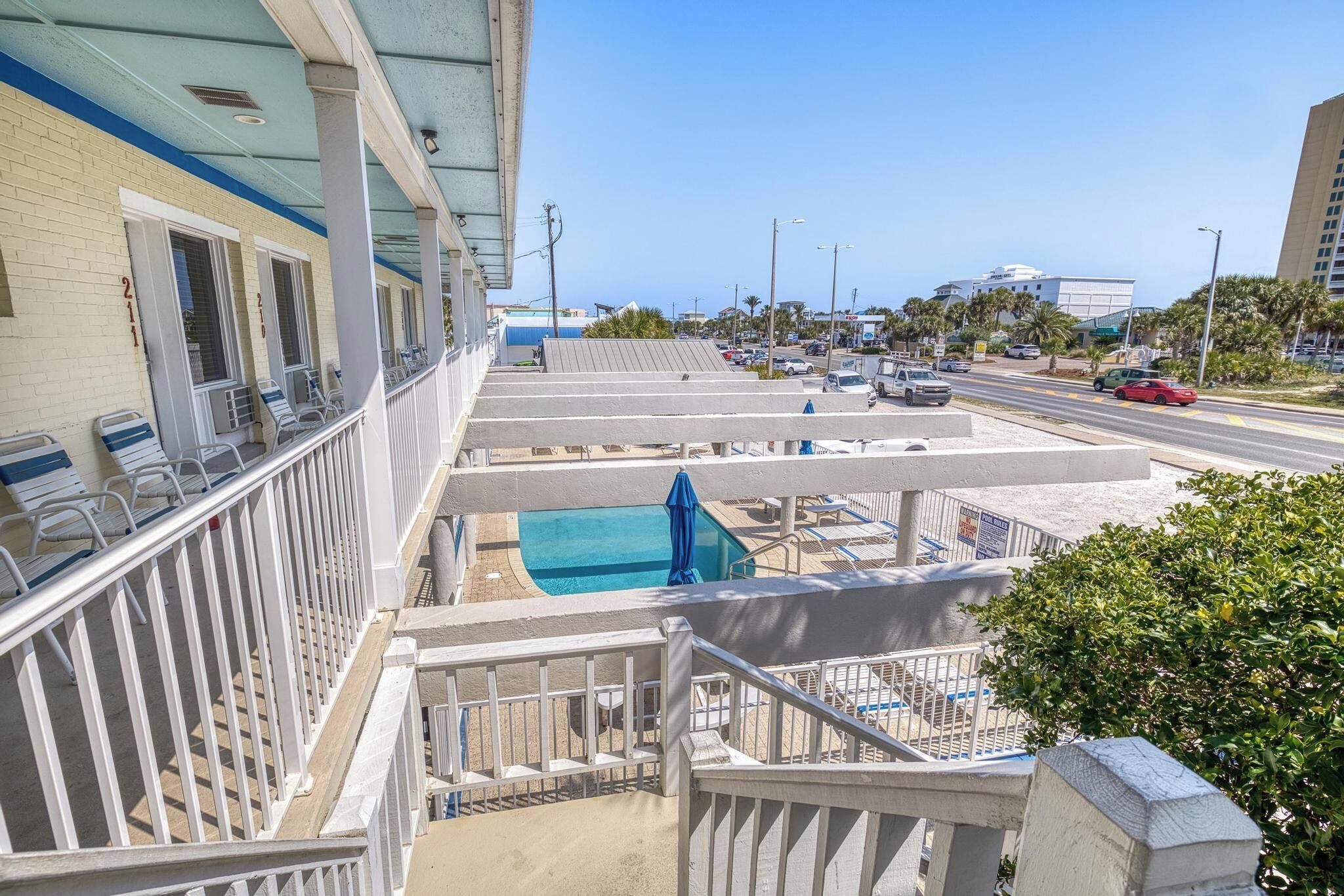 A hotel with a pool, outdoor seating, and a view of the street.