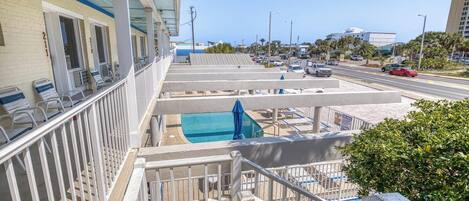 A hotel with a pool, outdoor seating, and a view of the street.