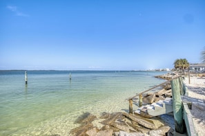 Vista despejada al agua con muelle de madera y costa rocosa.