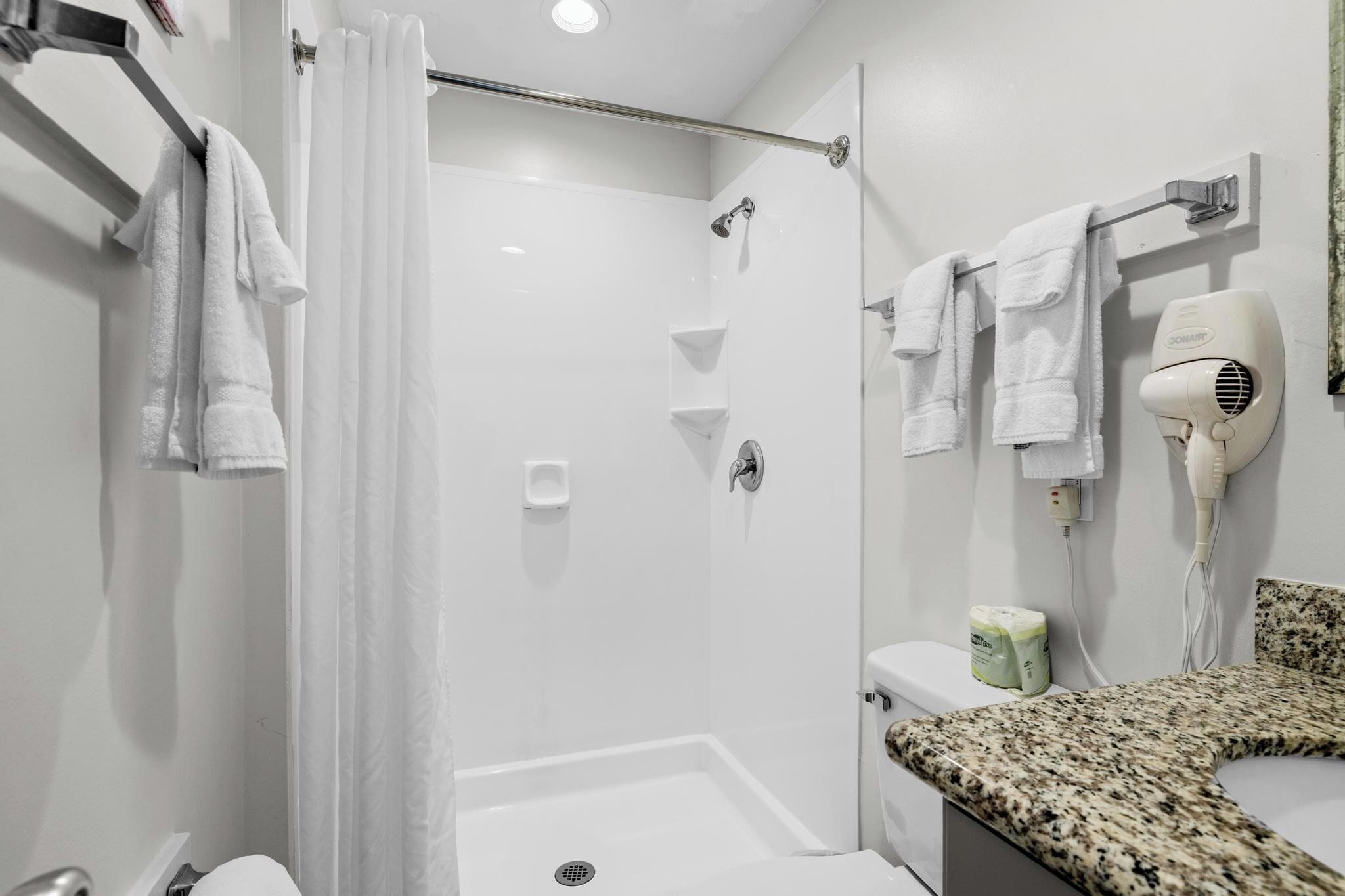 A modern bathroom with a shower, toilet, and hairdryer.